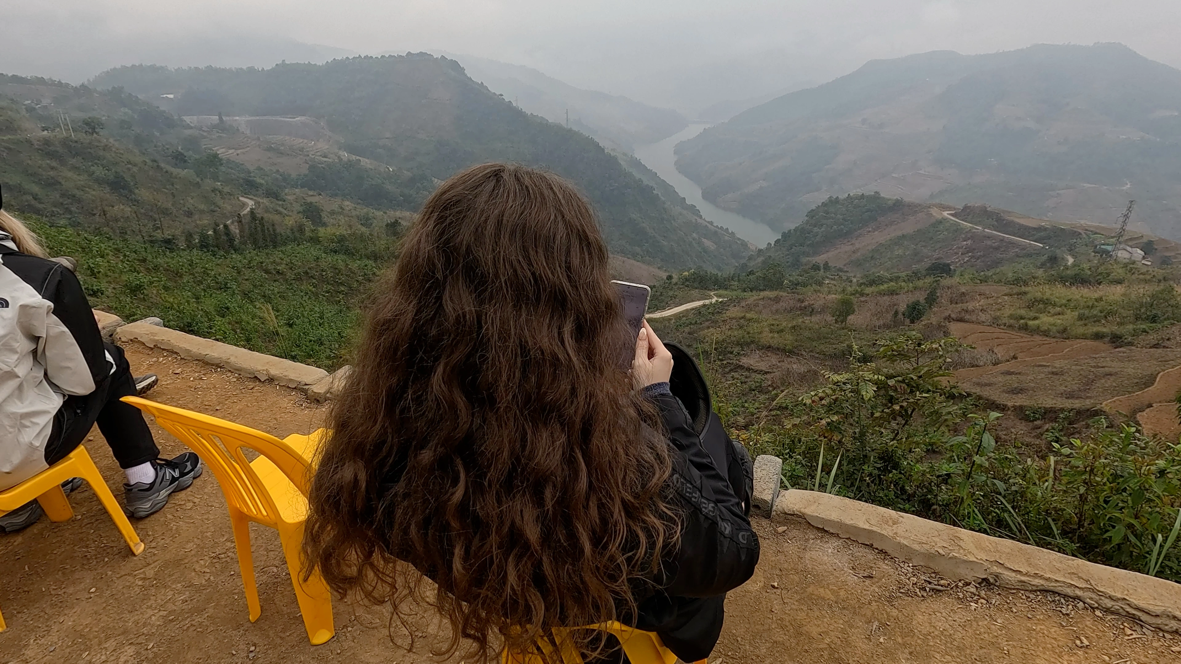 Sarah on her phone overlooking a mountain view in Vietnam