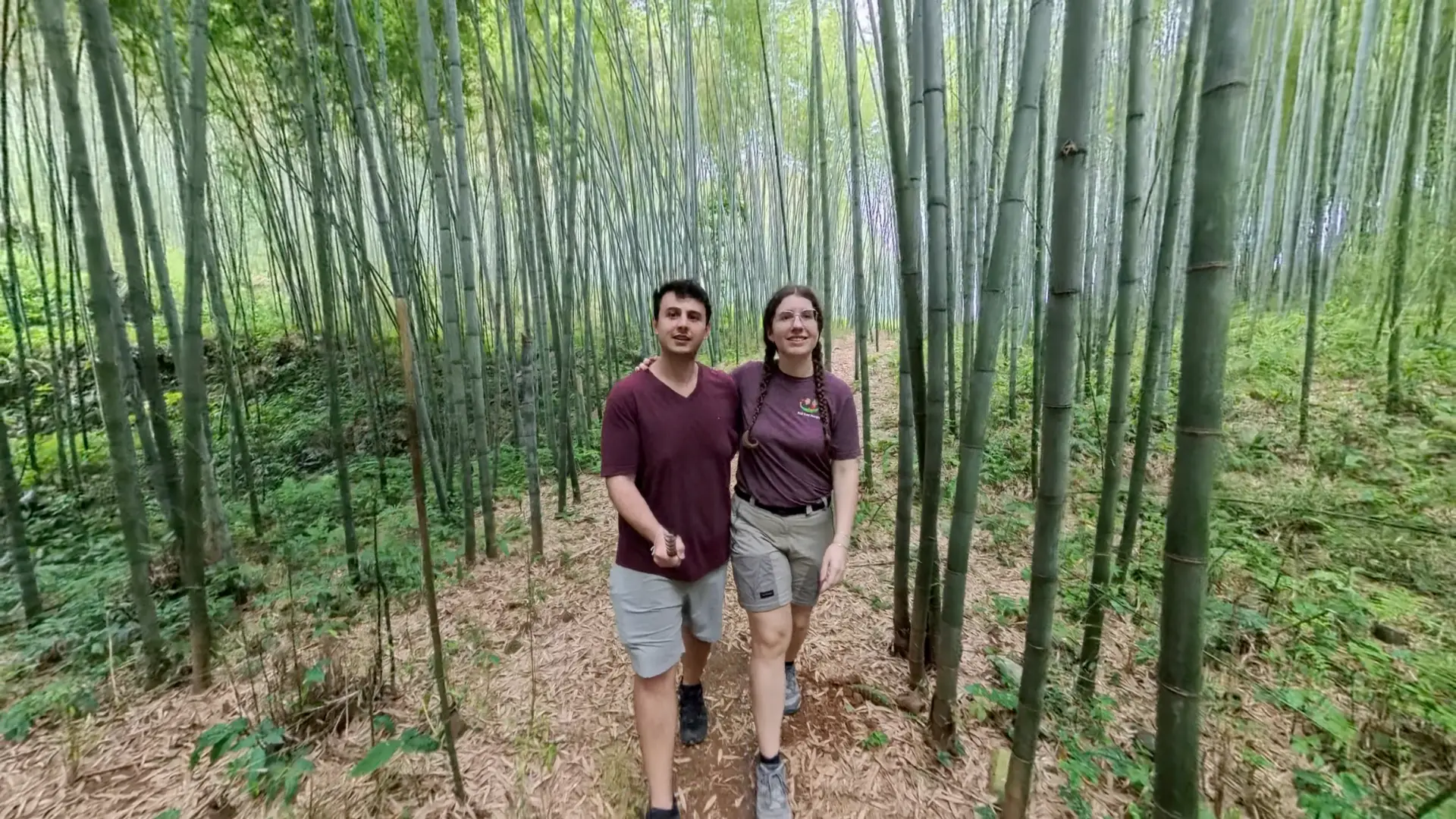 Liam and Sarah hiking a leaf-covered trail through a dense bamboo forest on the Ha Giang Loop, June 2026