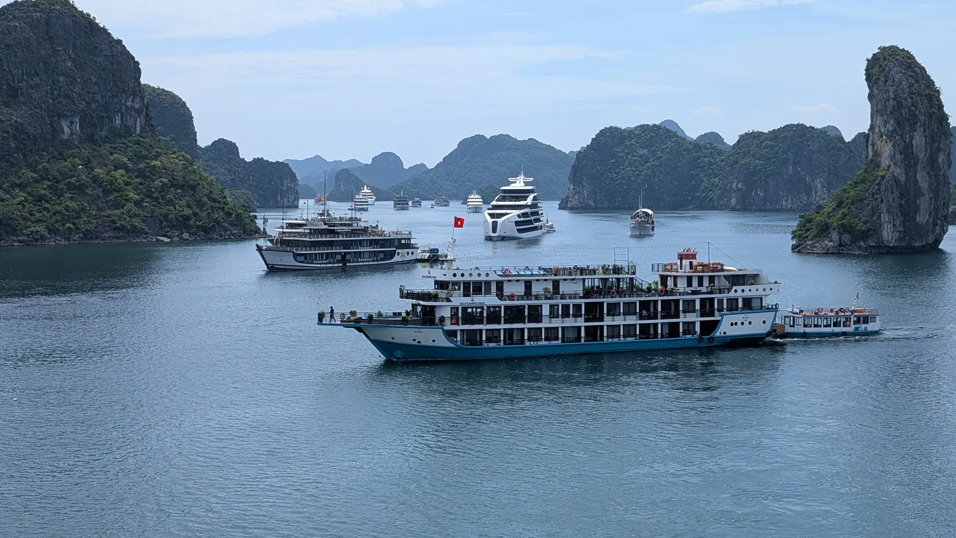 Lots of cruise boats sailing close together between the limestone islands of Ha Long Bay