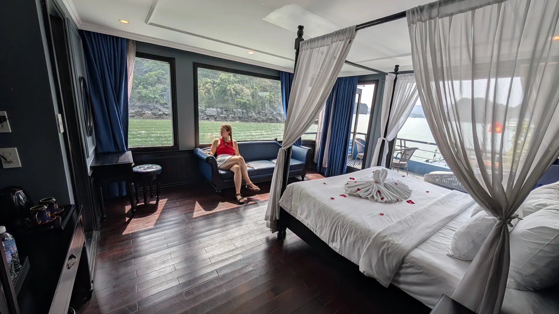 Sarah by the window in the Rosy Cruise honeymoon suite, with a rose petal four-poster bed and Ha Long Bay views