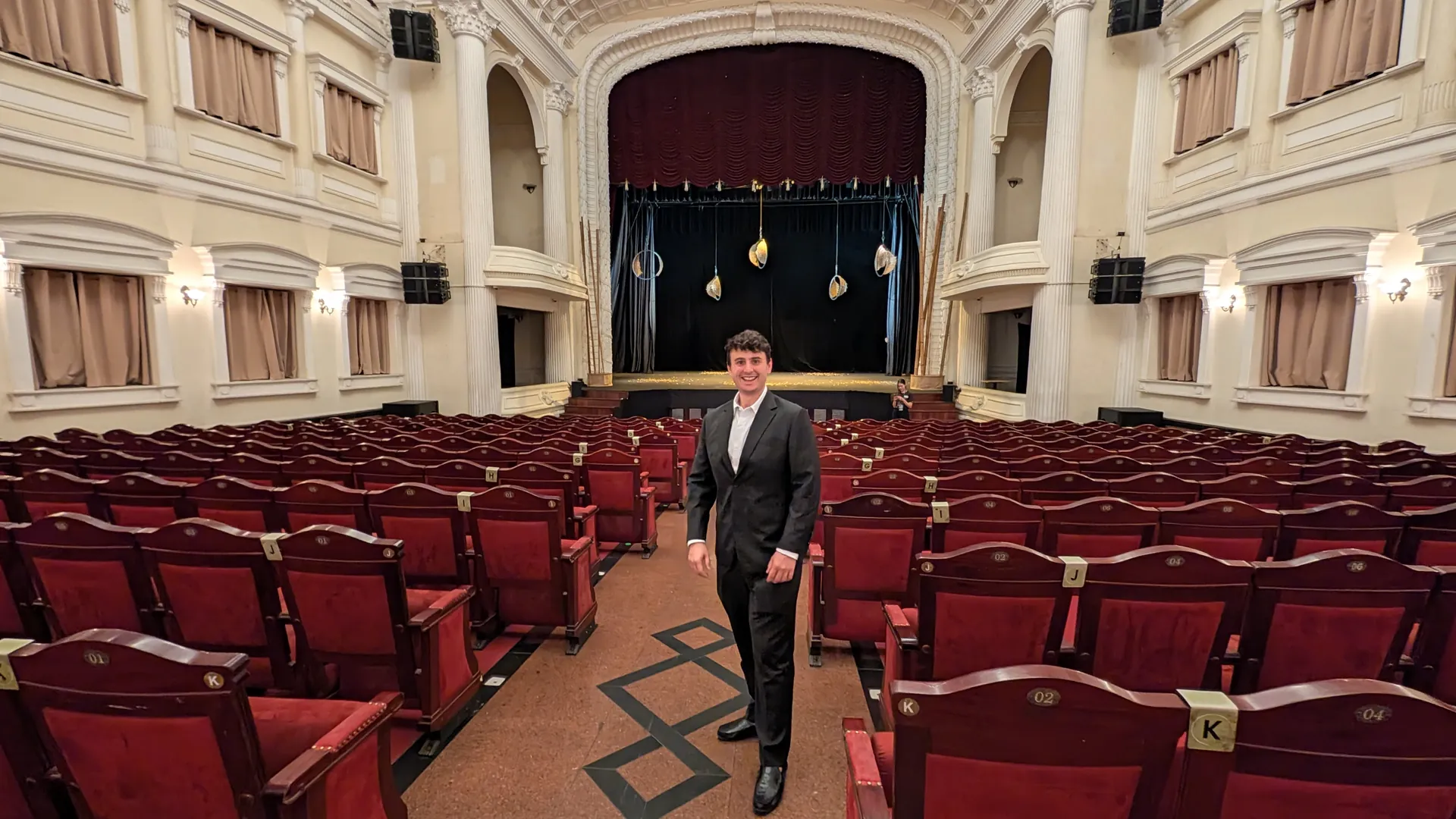 Liam in his black suit standing in the stalls of the Saigon Opera House