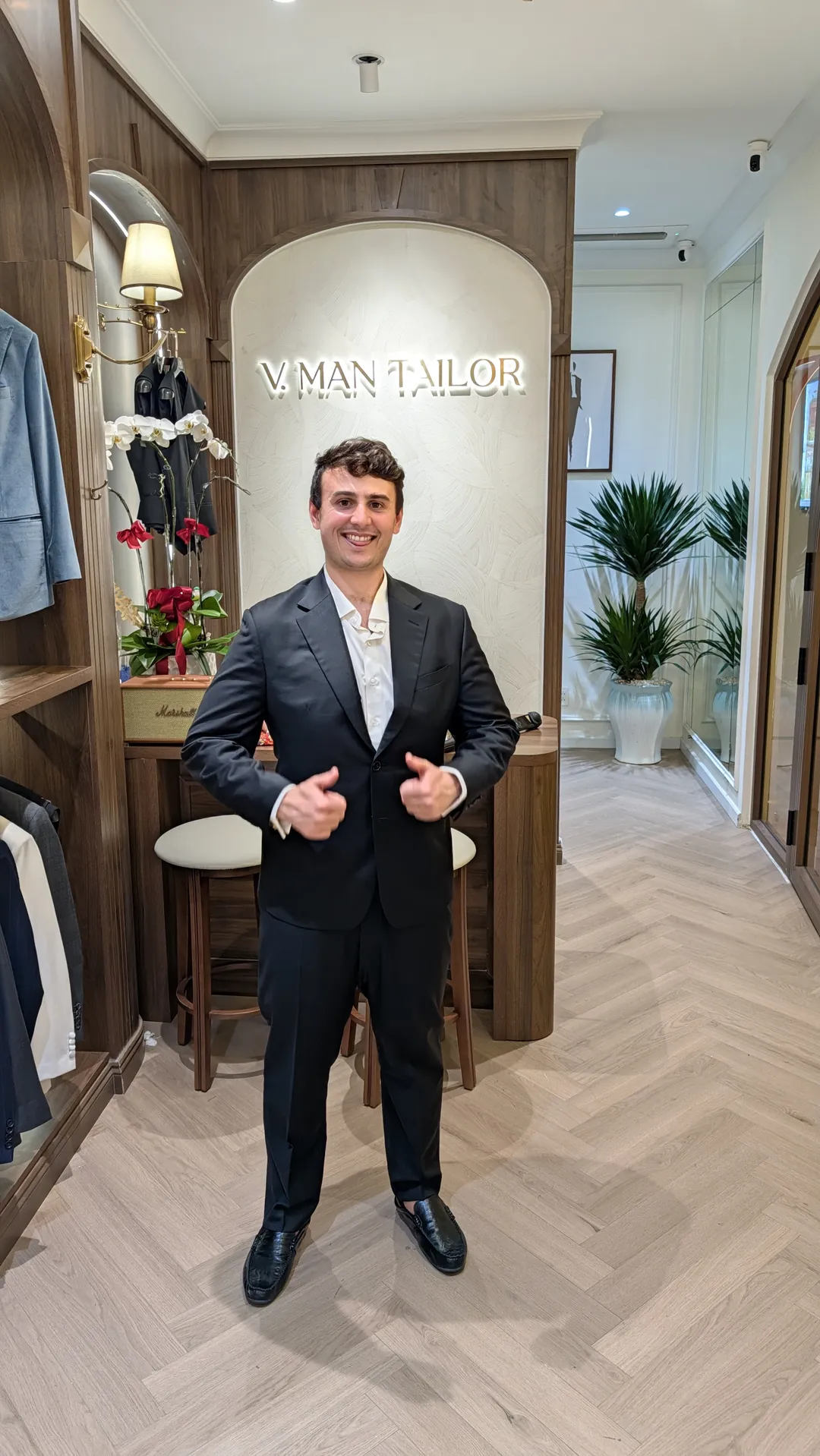 Full length shot of Liam in his black VMan suit in the shop