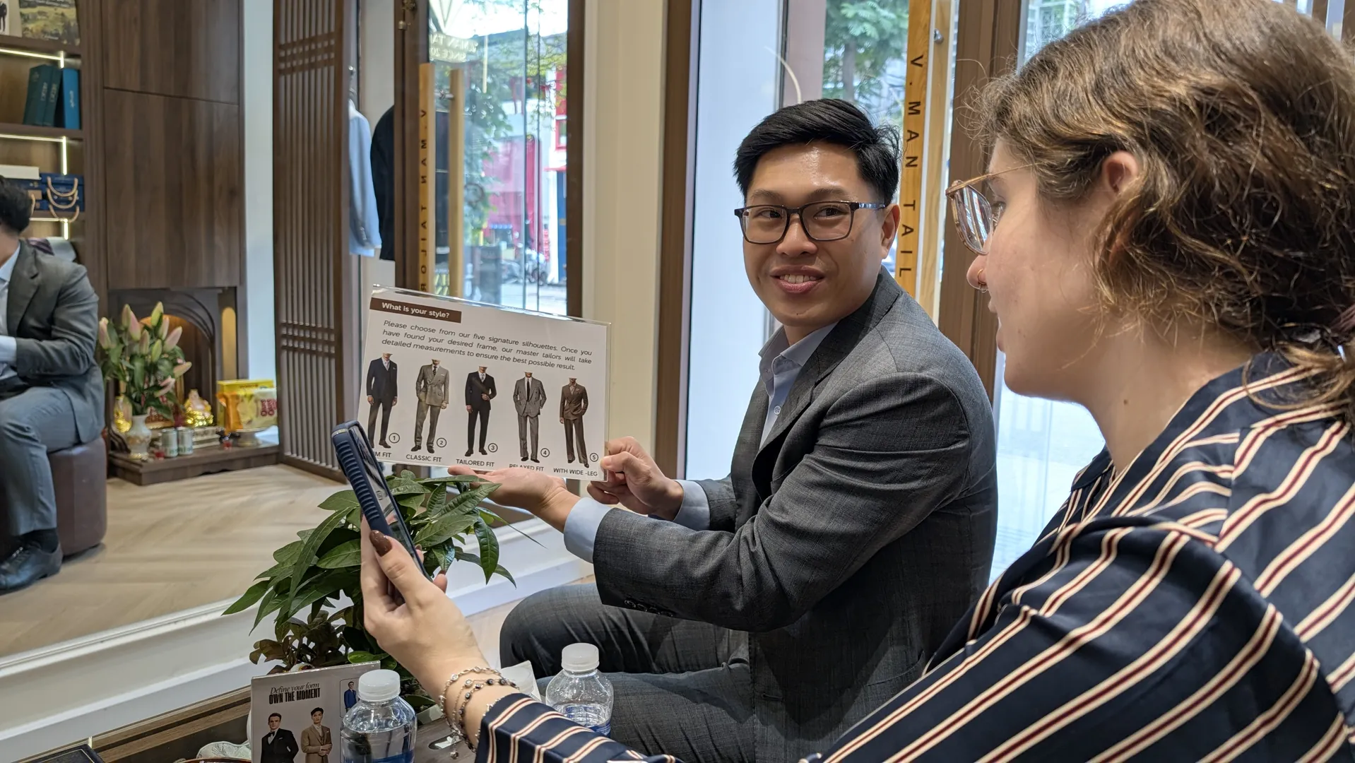 Sarah going through VMan Tailor's suit silhouette card with the team in the shop