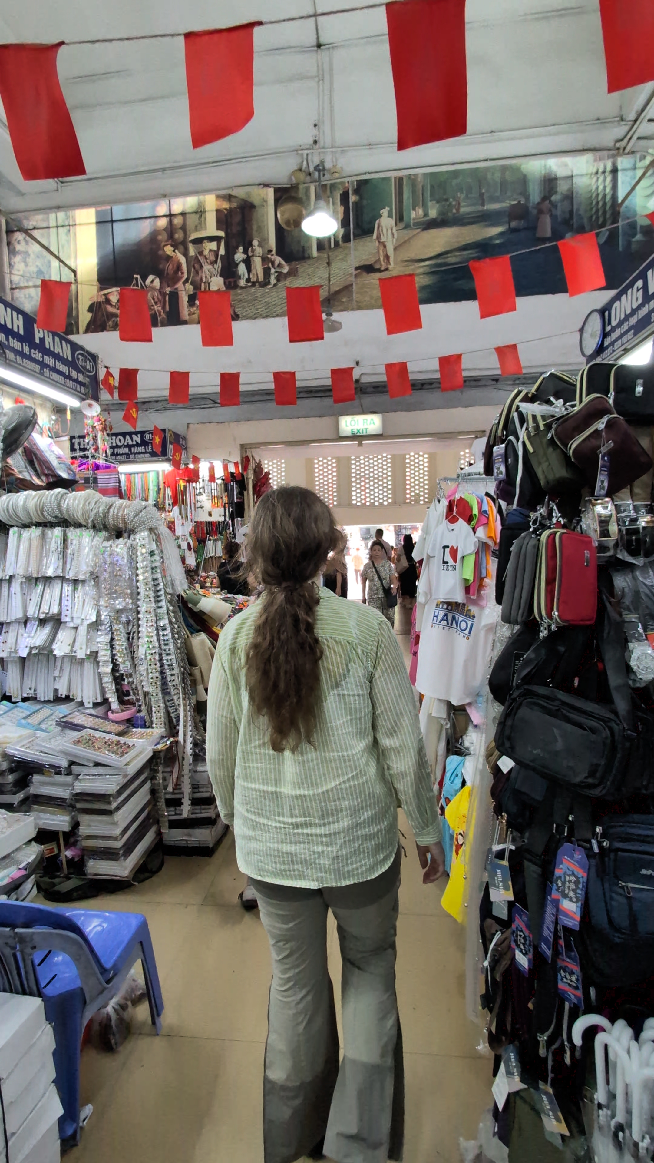 Liam and Sarah inside Dong Xuan Market in Hanoi with stalls selling coffee, snacks and souvenirs