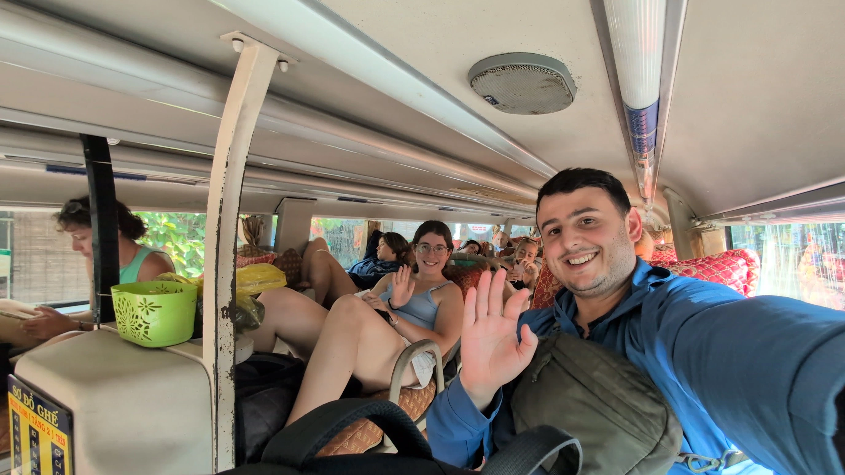 Liam and Sarah waving from berths on a crowded three-row sleeper bus in Vietnam