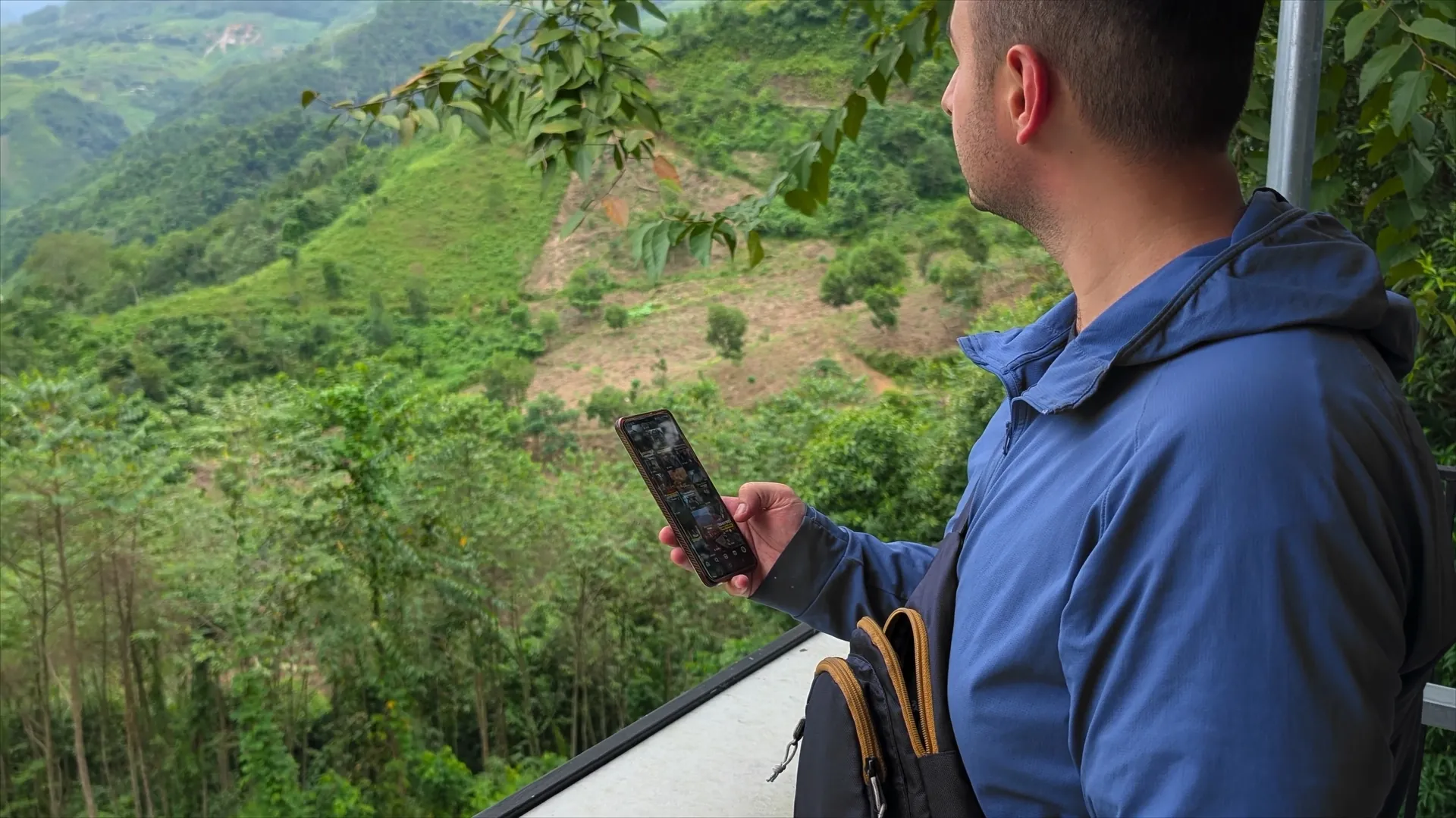 Liam checking his phone above green mountains in northern Vietnam, 2026.