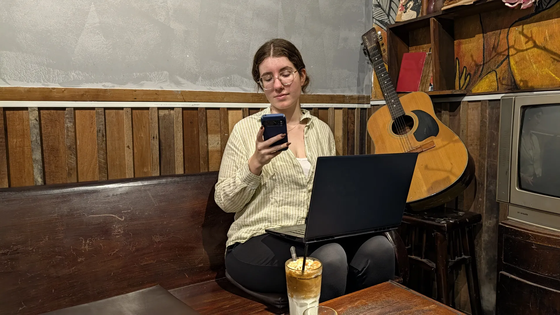 Liam at a cafe with a laptop and phone, Vietnam, October 2026.