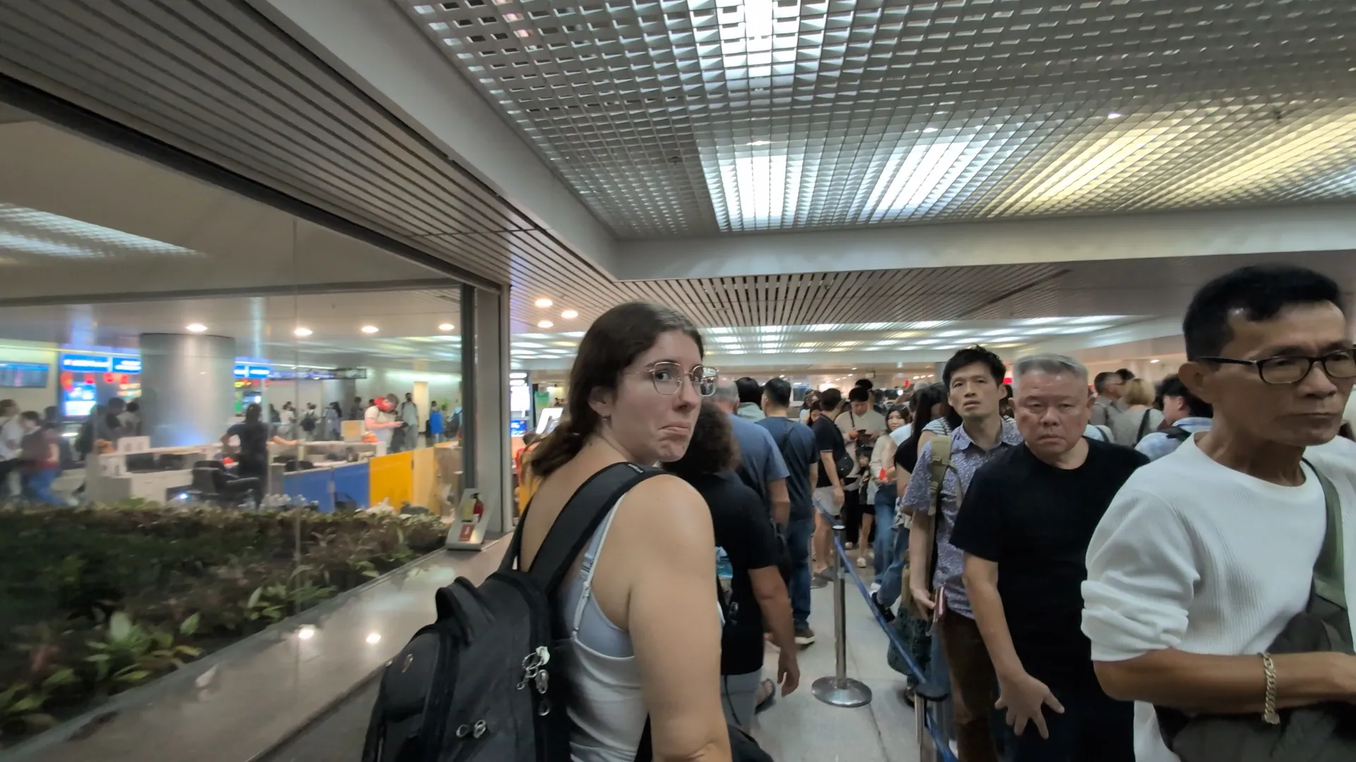 Sarah looking back unimpressed from a long regular immigration line at a Vietnam airport